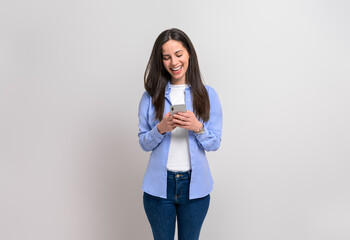 Cheerful female entrepreneur laughing and messaging over mobile phone on isolated white background