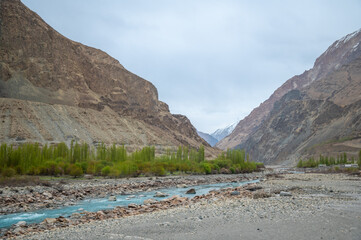 A river stream flows through a mountain landscape. Image of Shyok river in Turtuk, Ladakh