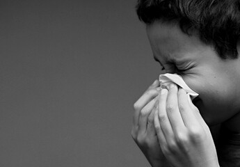 catching the flu child blowing nose after catching a cold with grey background with people stock...
