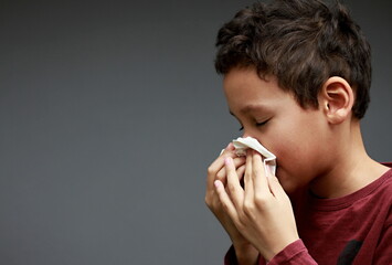 catching the flu child blowing nose after catching a cold with grey background with people stock...