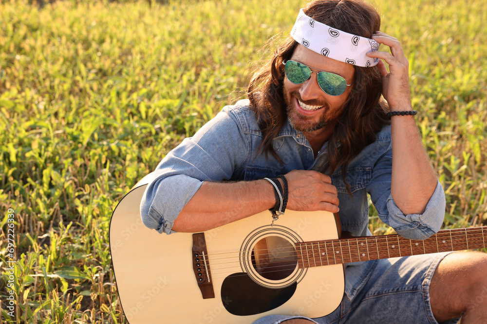 Poster Portrait of happy hippie man with guitar in field