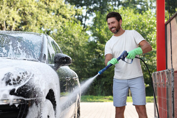 Man covering automobile with foam at outdoor car wash