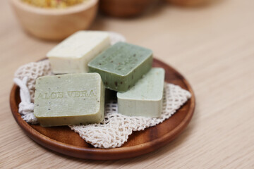 Tray with soap bars on light wooden table. Spa therapy