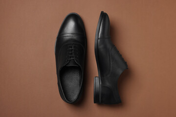 Pair of leather men shoes on brown background, top view