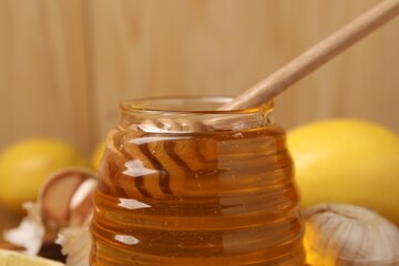 Jar with honey and dipper against blurred background, closeup