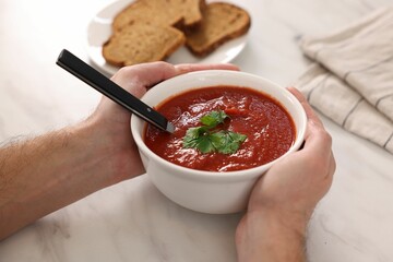 Man with delicious tomato soup at light marble table, closeup