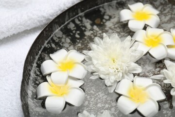 Fototapeta na wymiar Bowl of water with flowers and towel on table, closeup. Spa treatment