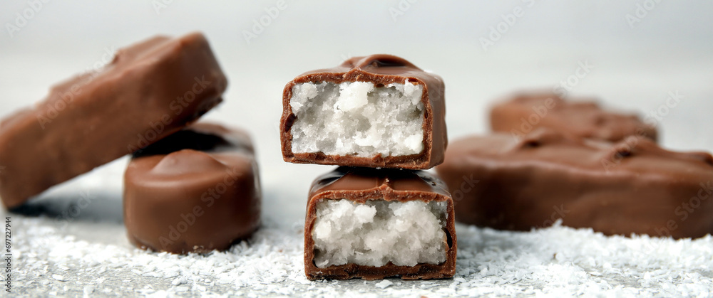 Wall mural delicious milk chocolate candy bars with coconut filling on grey table, closeup. banner design