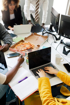 High angle view of female entrepreneur coding on laptop during meeting with colleagues at office