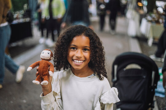 Portrait of happy girl holding toy monkey at flea market