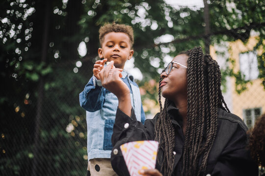 Low angle view of mother giving popcorn to son at amusement park