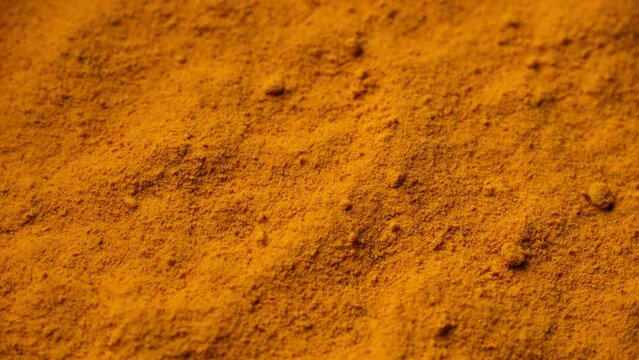 Zoom frame yellow turmeric powder top view, rotation. Condiment or dietary supplement
