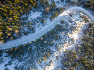 Road and rocks in winter coniferous forest. Aerial drone photography.