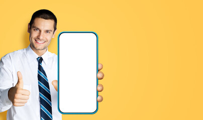 Excited smiling business man showing cell phone, mobile smartphone. Happy confident businessman...