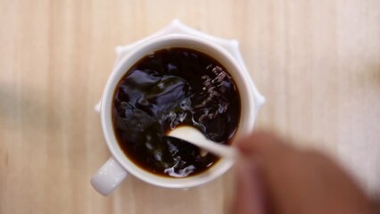 Top view of hand brewed black coffee in a cup with a spoon on a wooden table. Making coffee at home.