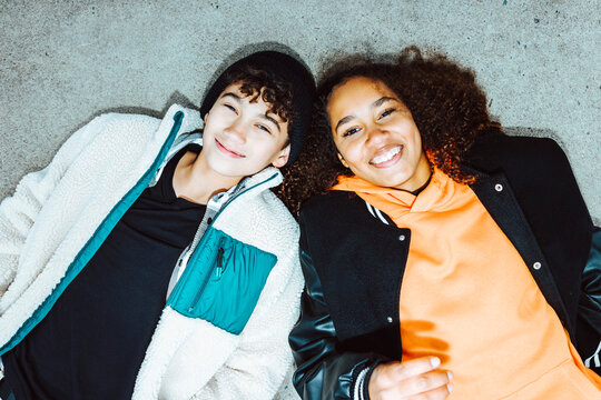 Portrait of smiling boy and girl lying on street