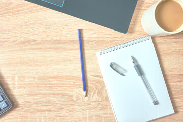 an open notepad for notes, a fountain pen, a pencil calculator, a cup of coffee and a laptop on a wooden table with a copy space, top view