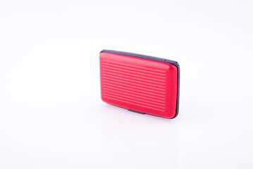 Red plastic credit card case on white reflective background.
