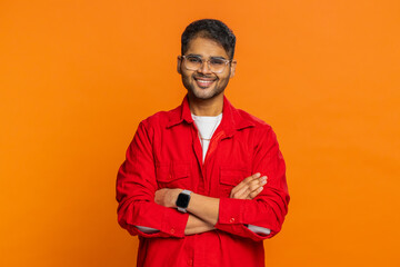 Cheerful lovely happy young Indian man smiling friendly glad expression looking at camera dreaming resting relaxation feel satisfied good news. Arabian bearded guy isolated on orange studio background
