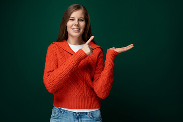 Beautiful slim woman with brown hair dressed in a red sweater and jeans on a green background