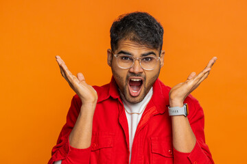 What. Why. Angry Indian man raising hands in indignant expression, asking reason of failure, demonstrating disbelief irritation by troubles, scream, shout. Arabian guy isolated on orange background - obrazy, fototapety, plakaty