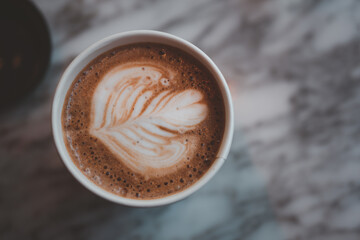 Mocha in a black paper cup. Morning delicious takeaway coffee. Top view of the foam . Creamy foam, fragrant coffee close-up. Fresh coffee