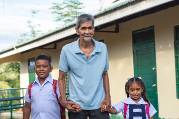 An asian grandad together with two of his grandkids in uniform. Fetching his grandchildren from a...