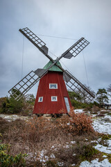 Typical historical red wooden windmill in a winter landscape. The building is located on a rock on the coast. Evening in Stenungsund, Sweden