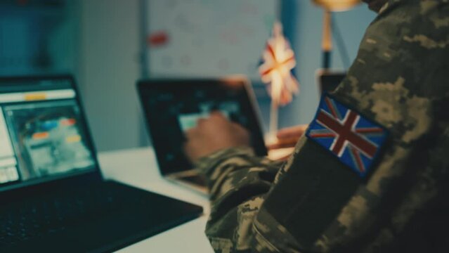 United Kingdom soldier working with gathered intelligence copying data on laptop
