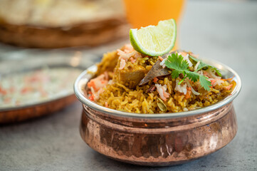 Spicy Indian biryani pulao in golden bowl with India basmati rice dish with chicken meat curry