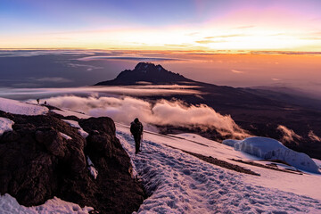 Hiker on the Kilimanjaro crater rim during sunrise behind Mawenzi peak