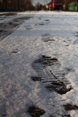 A snowy road with a person's foot prints in it