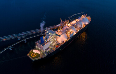 Aerial of Liquified Natural Gas LNG carrier moored to a small gas terminal at dusk. Fuel crisis. Sanctions