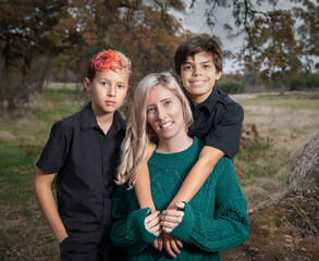 Smiling blonde mother outdoor portrait with two sons in autumn