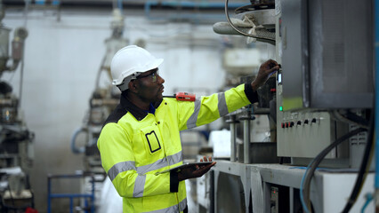 Engineer holding a digital tablet is checking the operation of a plastic machine. Worker inspects a CNC machine control board in Plastic factory.