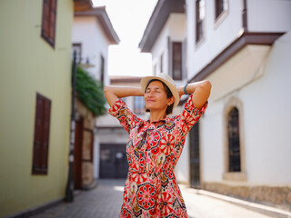female summer travel to Antalya, Turkey. young asian woman in red dress walk through old town...