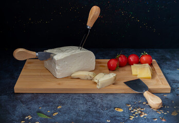 Black background. Various cheeses on wood.