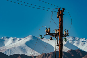 Old electric power line on snow covered mountains background