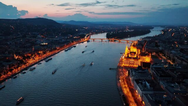 Cinematic shot of Orszaghaz at night. Breathtaking illuminated building of Hungarian parliament on Danube river waterfront. Budapest, Hungary