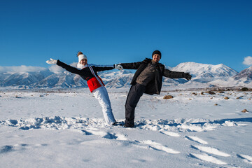 Fototapeta na wymiar Young happy couple of tourists on mountains background in winter