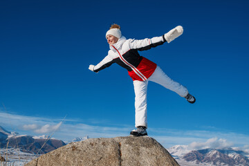 Happy woman tourist in swallow pose balancing on mountain landscape in winter
