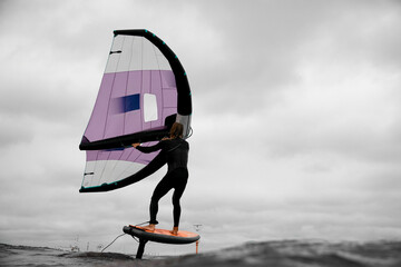 Male surfer standing on board holding wings for wingfoiling