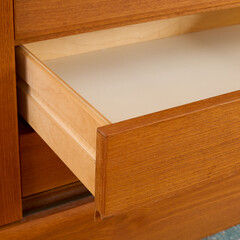 Late-Century teak credenza. Vintage wooden sideboard. Indoor detail photograph with open drawer. 