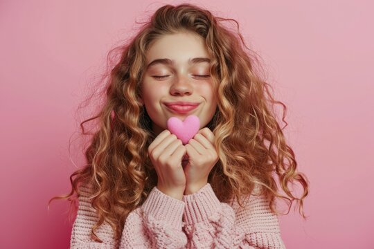 Beautiful teenager smiling while holding pink heart.
