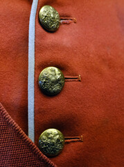 MIlitary brass butons on uniform red jacket. UK.