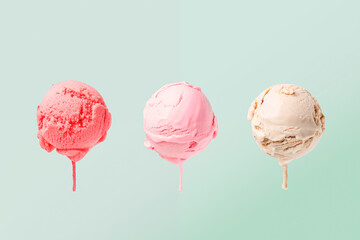 Three colorful scoops of cold sweet ice cream or gelato in assortment of different flavor of pink, green and beige color of vanila isolated on green mint background - obrazy, fototapety, plakaty
