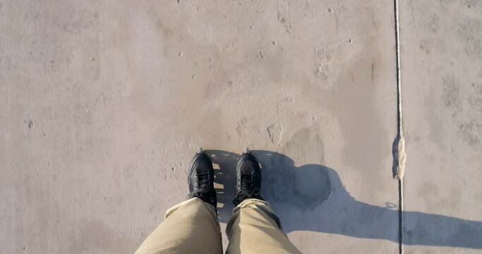 Man glides on inline skates along concrete road, gazing down at his boots and track surface. Speed gradually decreases until roller stops. First-person view shot captures his legs and tips of skates