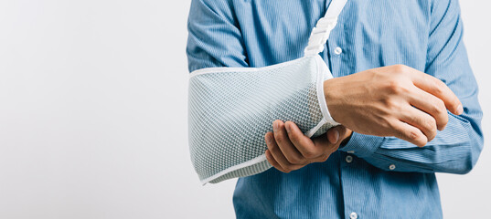 A resilient male with broken arm maintains smile while wearing splint for treatment, coping with...