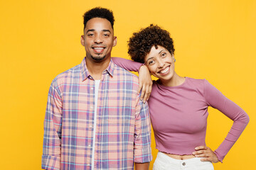Young smiling happy couple two friends family man woman of African American ethnicity wear purple casual clothes together wife put head on shoulder isolated on plain yellow orange background studio.
