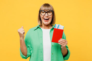 Traveler winner elderly woman 50s year old wear casual clothes hold passport ticket isolated on plain yellow background Tourist travel abroad in free time rest getaway Air flight trip journey concept